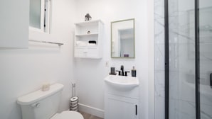 A modern bathroom with a toilet, sink, and shower. - 1 Bedroom Steps From Beach and Carlsbad Village (Carlsbad)