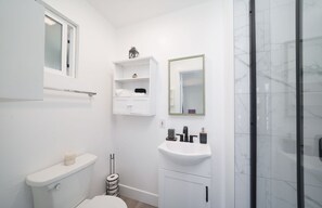 Ein modernes Badezimmer mit Toilette, Waschbecken und Dusche.