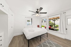 Ein Schlafzimmer mit Bett, Deckenventilator, Fenster mit Ausblick und Tür.