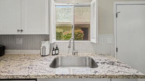 A kitchen with a herringbone tile backsplash, a stainless steel sink, and a window with white shutters. - NEW Camelback 352 Resort-style Stay Near Old Town (Scottsdale)