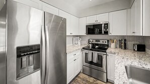 A modern kitchen with stainless steel appliances, a granite countertop, and white cabinetry. - NEW Camelback 352 Resort-style Stay Near Old Town (Scottsdale)