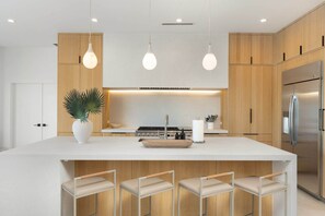 A modern kitchen with a central island, wooden cabinets, stainless steel appliances, and pendant lighting. - NEW The Dreyfus Resort Pool Designer Home (Scottsdale)