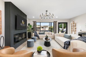 Ein modernes Wohnzimmer mit Flachbildfernseher, Kamin, Sofa, Couchtisch und einer Deckenleuchte.