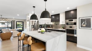A modern kitchen with a central island, bar stools, stainless steel appliances, and pendant lighting. - NEW The Barrington Ultra-luxe Designer Estate (Scottsdale)
