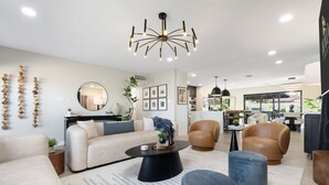 A modern living room with a sofa, armchairs, a coffee table, and a dining area in the background. - NEW The Barrington Ultra-luxe Designer Estate (Scottsdale)