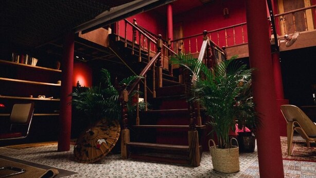 Eine Treppe mit Holzwangen, einer roten Wand und einem gemusterten Boden.