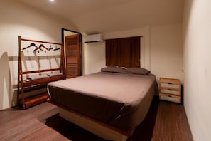 A bedroom with a bed, a wooden wardrobe, a hanging rack, a window with curtains, and a small wooden chest. - Hokma Boutique Hotel & Tropical Lounge (Ko Phi Phi)