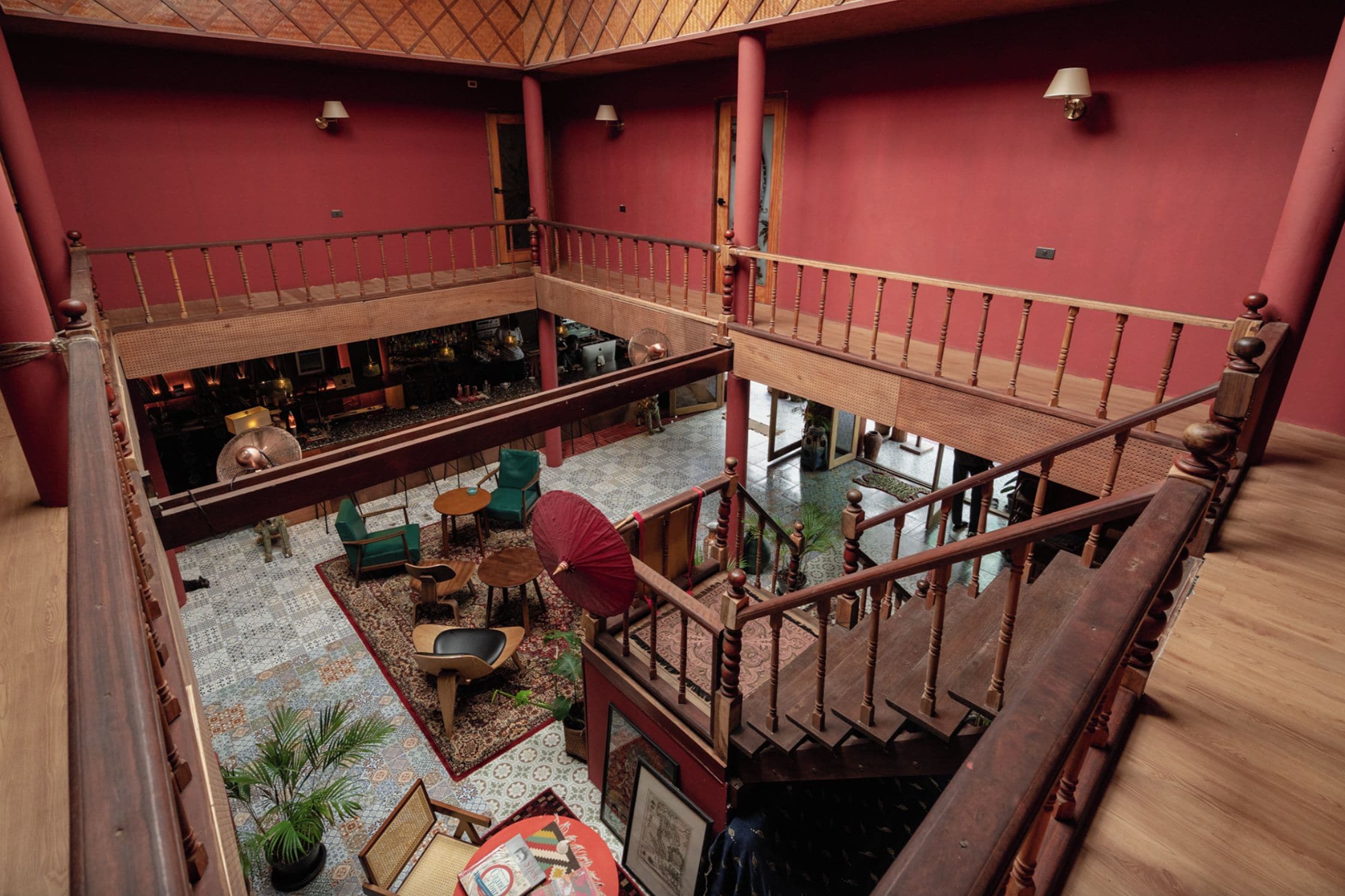 A multi-level interior with a wooden staircase, seating areas, and a view of the lower level.
