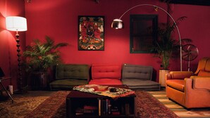 Ein Wohnzimmer mit einer Couch, Sesseln, einem Couchtisch, einer Lampe und einem Bild an der Wand.