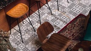 Eine Bar mit Barhocker, einem gemusterten Boden und einer Wandverkleidung.