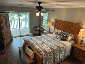 A bedroom with a bed, a bench, a dresser, a nightstand, a lamp, a ceiling fan, and a view through a sliding glass door. - Incredible lakefront spacious house with best view in town . Sleeps 15. (Granbury)
