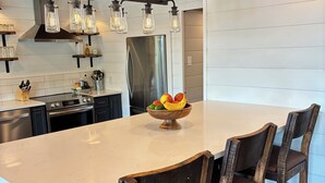 Una cocina moderna con una isla grande, electrodomésticos de acero inoxidable y sillas de madera.