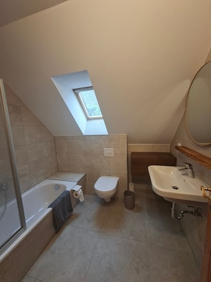 Un baño con tragaluz, bañera, inodoro y lavamanos.