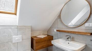 A modern bathroom with a built-in sink, a wooden vanity, a round mirror, and a window.