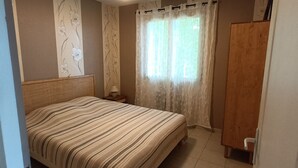 Ein Schlafzimmer mit einem Bett, Vorhängen, einem Nachttisch und einem Holzschrank.