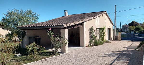 A single-story building with a tiled roof, a gravel driveway, and a metal gate.