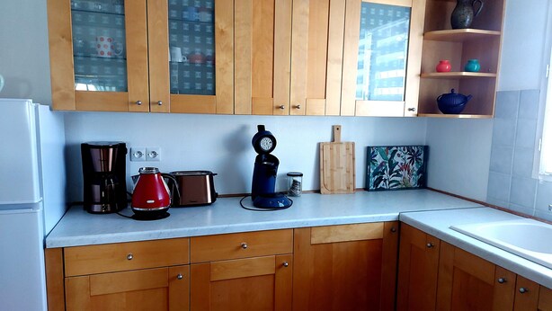 Eine Küche mit Holzausstattung, einer Kaffeemaschine, einem Toaster, einem Wasserkocher, einem Schneidebrett und einem Regal mit Dekoration.