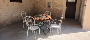 A rustic outdoor dining area with a round table and four metal chairs.