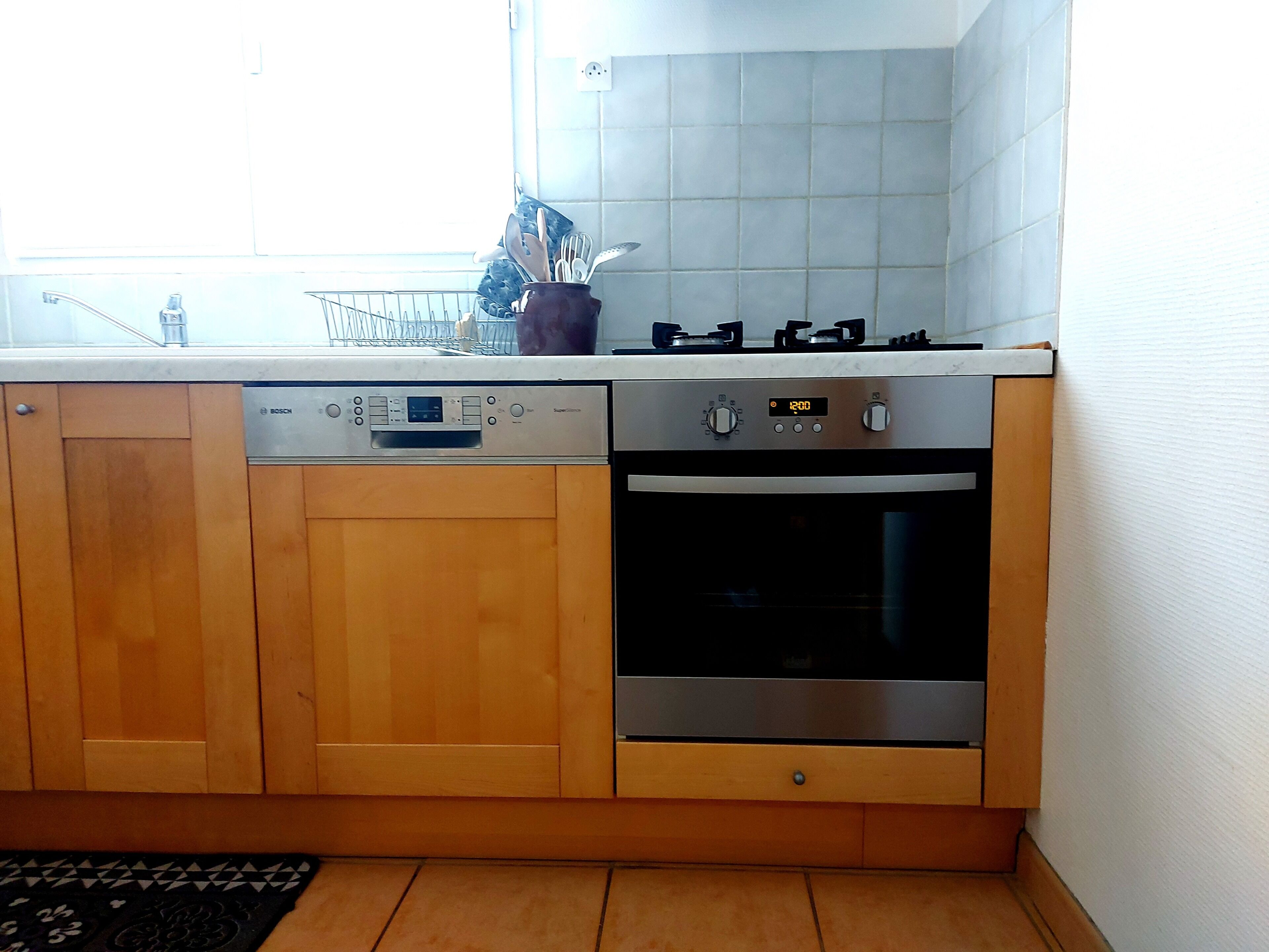 A kitchen with wooden cabinets, a Bosch dishwasher, a stove, and an oven.