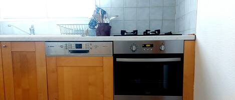 A kitchen with wooden cabinets, a Bosch dishwasher, a stove, and an oven.