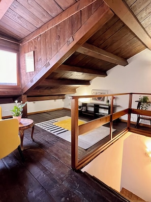 A wooden interior with a sloped ceiling, a dining area with a table and chairs, and a small plant on a table. - La Casetta—2-Bedroom Apartment in the Heart of Venice (Venezia)