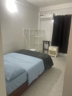 A bedroom with a bed, a white wardrobe, a small table, a hanging rack, and an air conditioning unit. - Apart Gaviotas #5 (minimum 4, maximum 6 guests) (San Andrés)
