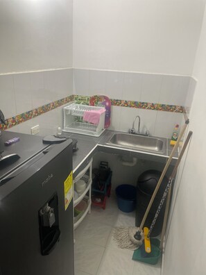 A compact kitchen with a sink, a dish rack, a mop, and cleaning supplies. - Apart gaviotas #5 ( minimum 4 and maximum 6 guests) (San Andrés)