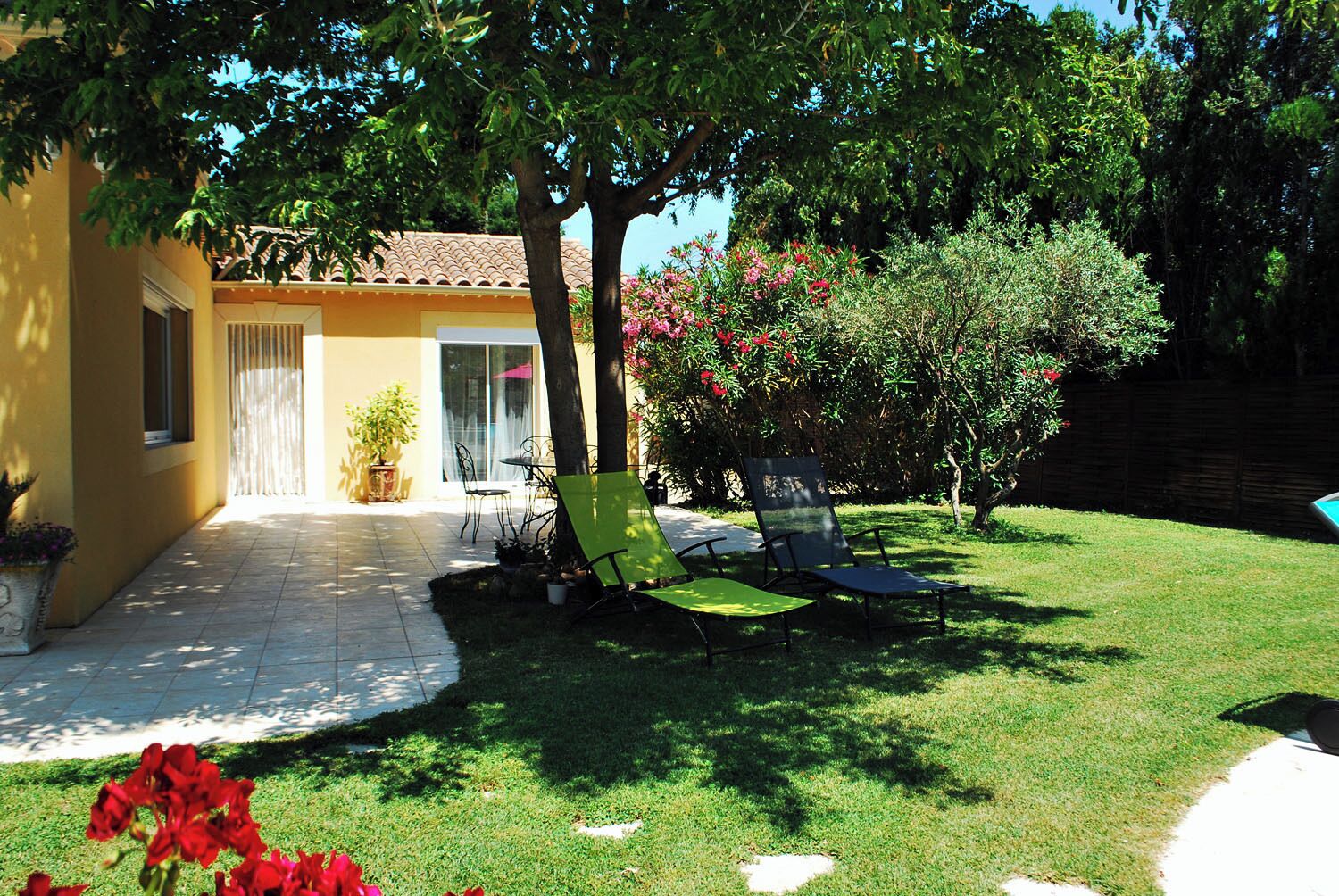 Un patio con mobiliario de jardín, sillas, una mesa y un pequeño jardín.