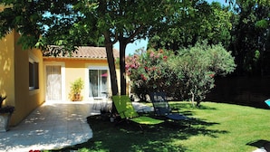 Um pátio com cadeiras, mesa e um pequeno jardim.