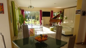 Uma sala de jantar com mesa de vidro, cadeiras e uma tigela de frutas.
