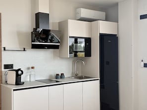 A compact kitchen with a coffee maker, a microwave, a sink, and a refrigerator.