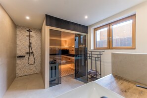 Une salle de bain moderne avec une douche, un dressing ouvert délimité par des parois en verre et une fenêtre.