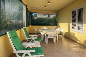 Ein Balkon mit Stühlen und einem Tisch, Blick auf Grünflächen, und ein Gebäude im Hintergrund.