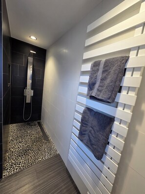 A modern bathroom with a shower, a towel rack, and a patterned floor.