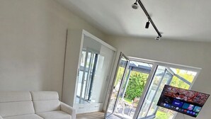 A modern hotel room with a bed, a sofa, a small round table, and a TV mounted on the wall. - All-In Rhein-Main - Pool, Hot Tub, Sauna, Fitness Center & Workspace! (Ginsheim-Gustavsburg)