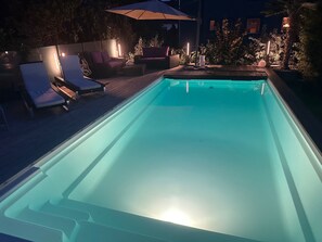 A swimming pool with lounge chairs and a wooden deck.