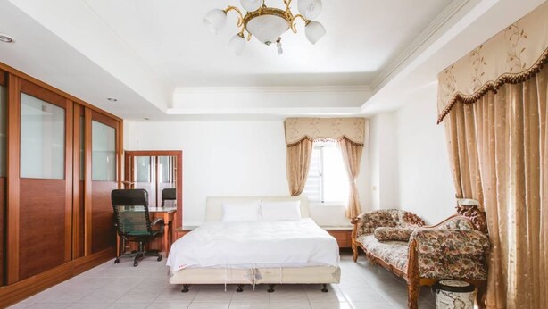 A bedroom with a bed, a desk, a chair, a sofa, and a chandelier. - HeartBnb Villa (Taitung)