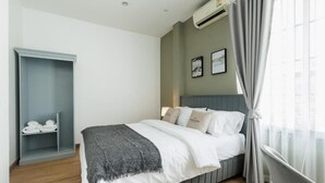 Quarto com uma cama, um guarda-roupa cinzento, uma cadeira cinza e uma janela com cortinas.