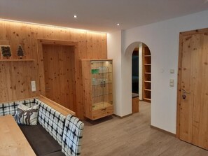 Une pièce avec un banc en bois, une vitrine et une porte en bois.