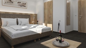 A hotel room with a bed, a bedside table, a framed picture on the wall, and a table with a bottle and glasses. - Viktoria (Sankt Anton am Arlberg)