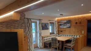 A cozy room with a wooden bench seating area, a flat-screen TV, and a stone wall. - Viktoria (Sankt Anton am Arlberg)