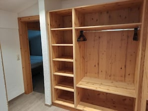 A wooden wardrobe with multiple shelves and hanging space.