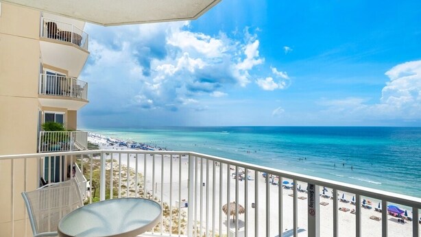 Ein Balkon mit Blick auf einen Strand, inklusive Tisch und Stühlen.