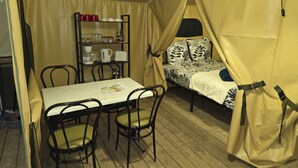 A tent with a bed, a table with chairs, and a shelf with kitchenware. - The Safari Lodge Tent We offer you unusual accommodation (Souleuvre en Bocage)