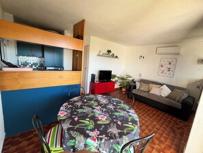 Ein gemütlicher Wohnbereich mit Küchenzeile, Esstisch, Sofa und Fernseher.