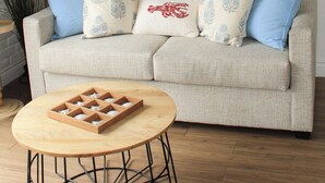 Ein Wohnzimmer mit einer Couch, einem runden Holztisch und einem Bild eines Segelboots an der Wand.