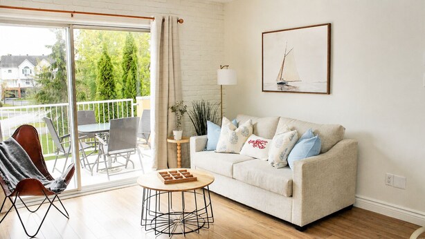 Ein Wohnzimmer mit einer Couch, einem Couchtisch, einem Sessel, einer Lampe und einem Gemälde.