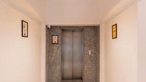 An elevator in a hallway with a tiled floor and plain walls. - Itsy Hotels Cozy Retreat - Near Mysore Palace & Zoo (Mysore)