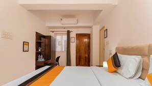 A hotel room with a bed, a desk, a chair, a wardrobe, and a door. - Itsy Hotels Cozy Retreat - Near Mysore Palace & Zoo (Mysore)