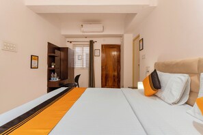 A hotel room with a bed, a desk, a chair, a wardrobe, and a door. - Itsy Hotels Cozy Retreat - Near Mysore Palace & Zoo (Mysore)